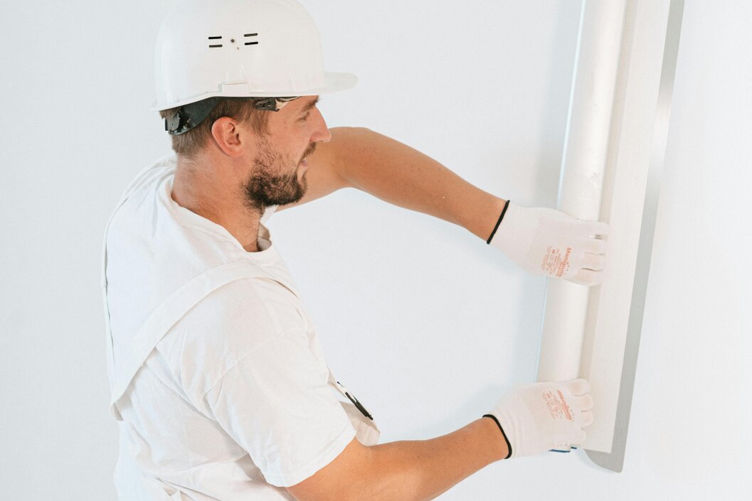 Hand trägt Putz auf eine Wand auf